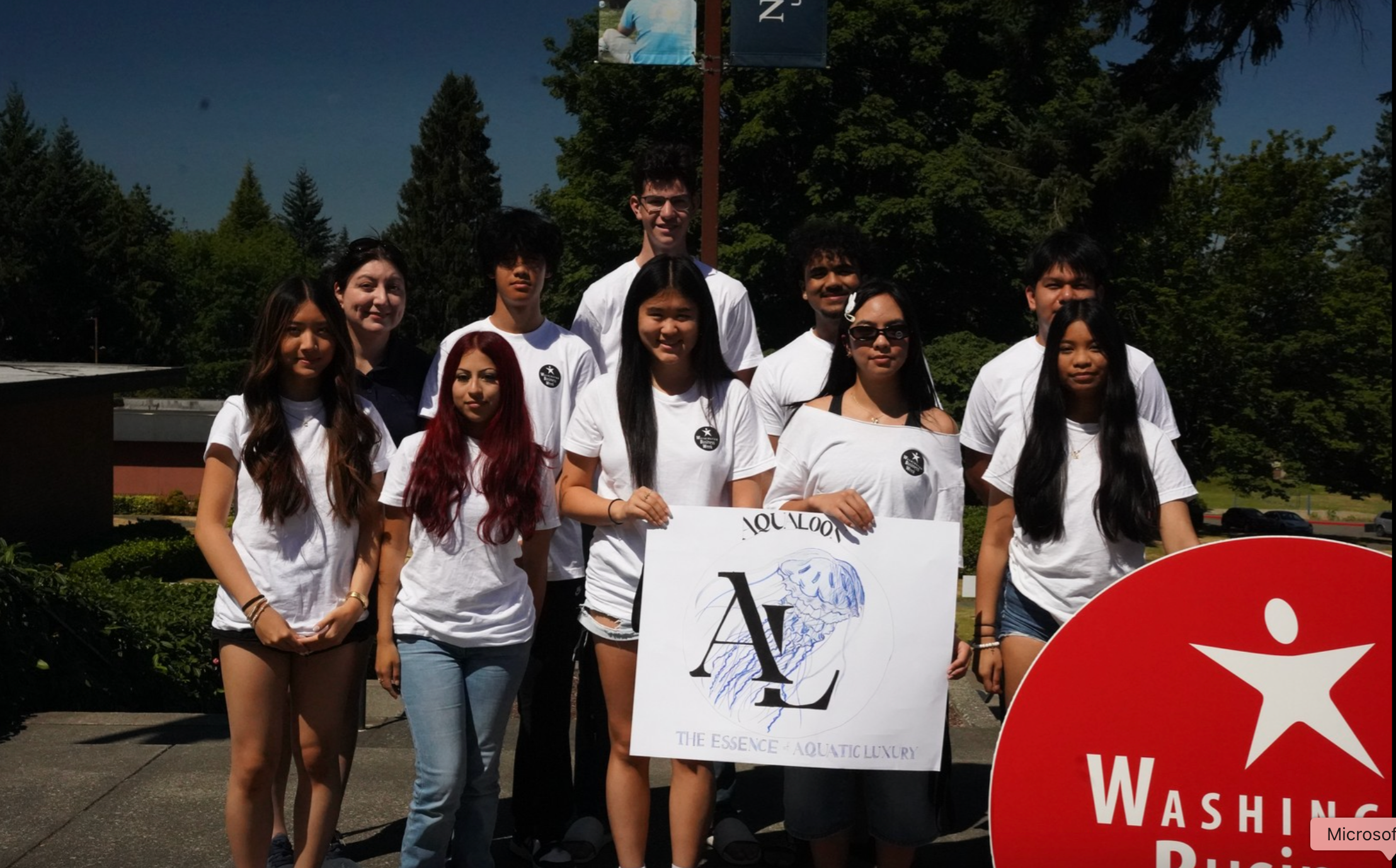 Yesha with her Washington Business Week team in 2025, holding the Aqua Loor company logo she designed
